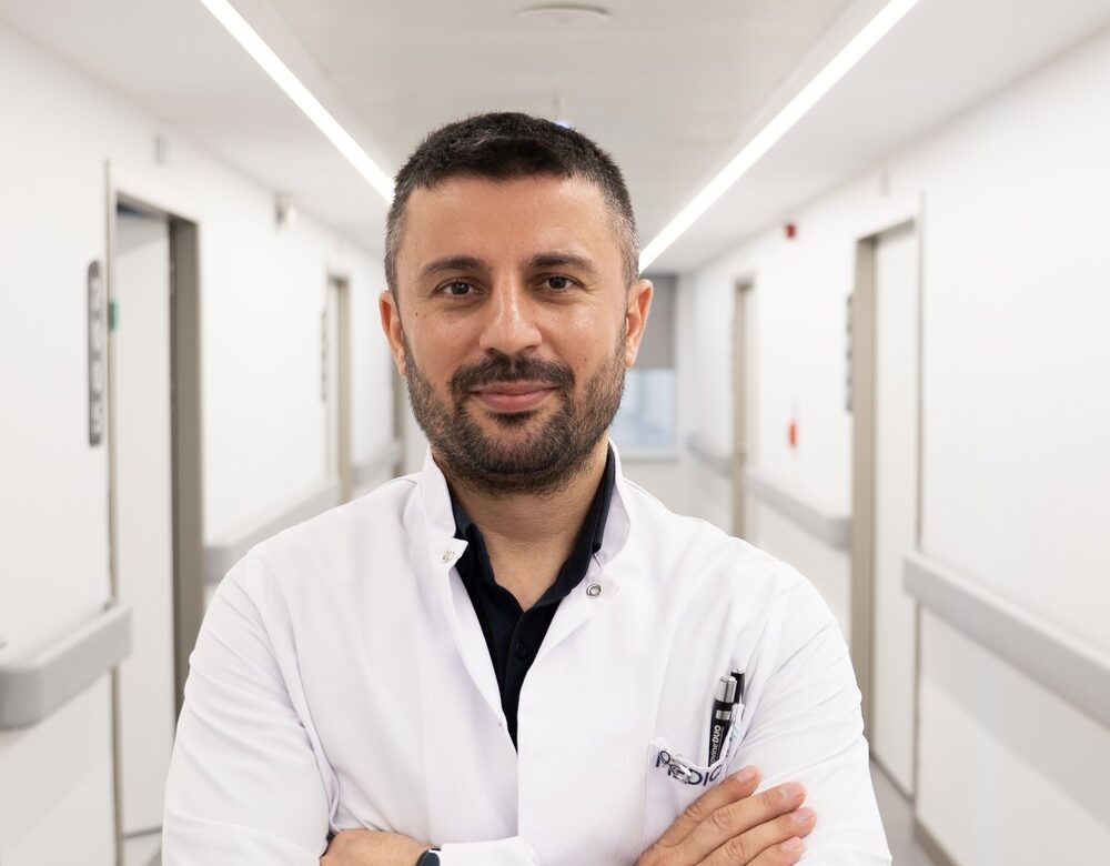 Dr. Dündar Parlak, klinik koridorunda beyaz önlüğüyle